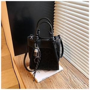 Détail du sac seau léopard avec poignée nouée et breloque décorative à pompon et perles