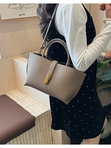 Detail of taupe grained leather tote bag with gold oval buckle shown on a model
