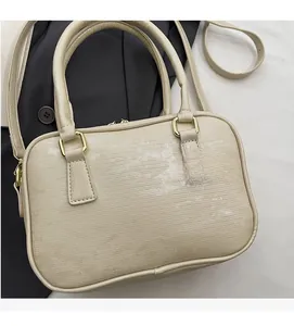 Close-up of beige Epi textured Boston bag with golden hardware on dark blazer