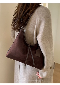 Détail du sac hobo en daim marron foncé avec nœud en cuir porté par un mannequin