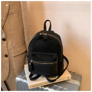 Détail du mini sac à dos en daim noir avec surpiqûres blanches et ferrures dorées chic
