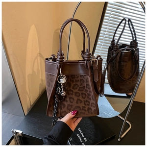 Détails d'un sac seau marron avec empiècement léopard et pendentif à pompon