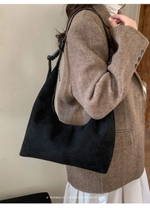 Detail of black suede dumpling bag showing matte texture and knotted leather strap