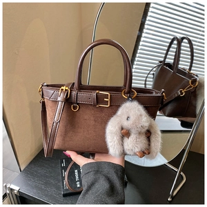 Macro detail of vintage brown tote bag with suede panels and plush rabbit accessory