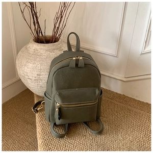 Détail du sac à dos en similicuir vert olive avec fermetures éclair dorées et poches latérales