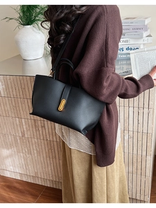 Detailed close-up of black lychee grain leather tote bag with elegant gold metal lock