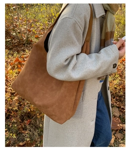 Detail view of large brown frosted leather tote bag with long shoulder strap