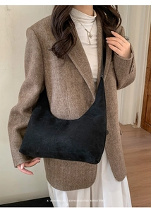 Detail of minimalist black suede hobo bag styled with a vintage blazer on model