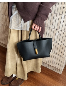 Detail of black pebbled leather bucket bag with elegant gold oval twist-lock closure