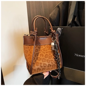 Détail d'un sac seau léopard avec poignée en cuir nouée et accessoire de sac tissé