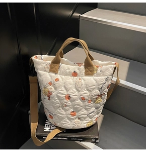 Detail of white quilted tote bag featuring cartoon bear prints and brown carry handles