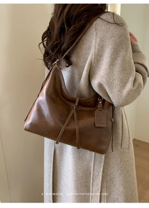 Détail d'un sac hobo en cuir huilé marron foncé avec bandoulière et nœud décoratif élégant