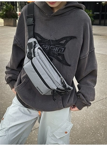 Close-up of grey checkered crossbody bag with adjustable wide strap and quick release buckle