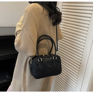 Model wearing a black Boston suede handbag with textured finish and golden zippers