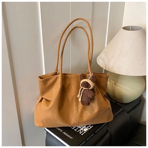 Detail of khaki leather tote with vintage texture and cute plush bear charm accessory