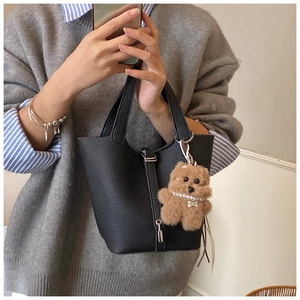 Detalle de bolso tipo cubo en cuero negro con grabado lichi, cierre plateado y adorno