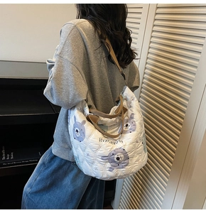 Quilted white tote bag with purple bear pattern shown on model in home setting