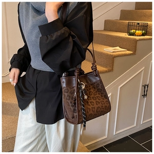 Détail du sac seau à imprimé léopard avec bordure en cuir marron et pompons