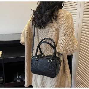 Detail of retro black textured suede Boston bag with gold hardware shown on model back