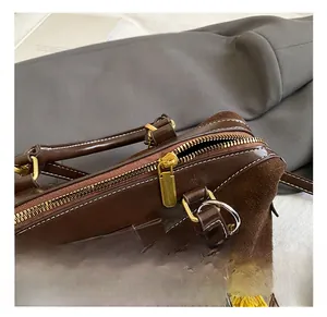 Close-up of dark brown suede pillow bag featuring gold zipper and metal hardware