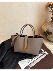 Close-up of taupe litchi grain leather bag with elegant gold clasp and dual handles