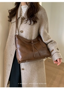 Gros plan d'un cabas en cuir marron rétro avec pompon et pieds en métal sur manteau