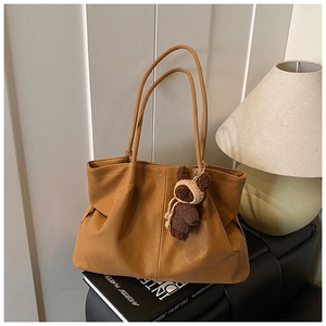 Detailed macro view of brown faux leather tote bag with a cute bear plush toy accessory