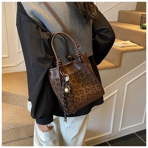 Détail du sac à main léopard avec rabat en cuir marron et pompon tressé élégant