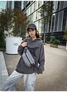 Detail of gray checkered chest bag with adjustable strap and functional black zippers