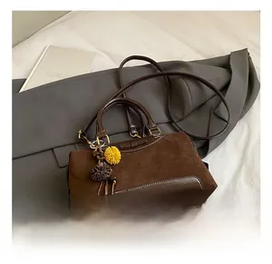 Detail view of vintage dark brown tote bag with decorative bow and plush pom-pom charms