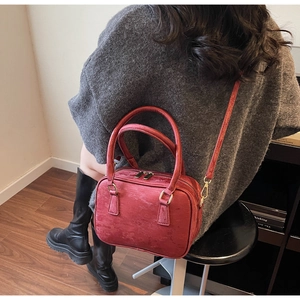 Model wearing a deep red suede Boston bag with striped texture and golden hardware