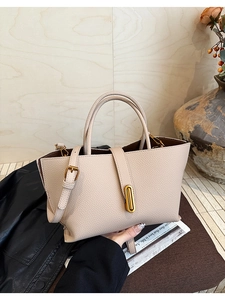 Detailed macro view of pebble grain leather texture and gold hardware on beige tote bag