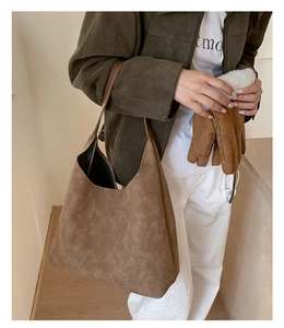 Detail of a large brown suede tote bag styled with an autumn jacket for a chic look