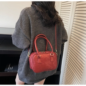 Macro shot of retro brick red suede boston bag with detailed texture and gold hardware