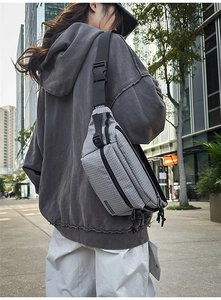 Close-up of grey grid texture chest bag with multi-pocket zippers and tactical buckle strap
