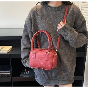 Detail view of brick red suede Boston bag with horizontal embossing and gold hardware