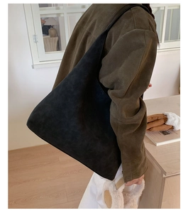 Detail of the black suede hobo bag texture and wide strap on a model for autumn style