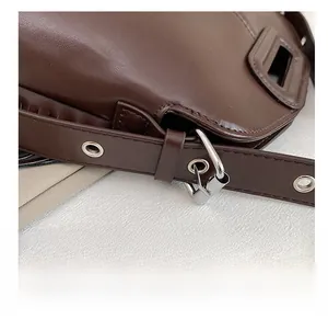 Detail of adjustable dark brown leather shoulder strap with silver metal buckle and hook