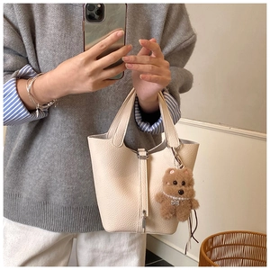 Detalle del bolso cubo de piel granulada con cierre metálico y adorno de oso pequeño