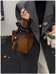 Détail du sac seau à imprimé léopard avec poignée nouée et breloques de mode