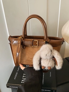 Vintage brown leather tote bag with buckle detail and plush bunny pendant on book