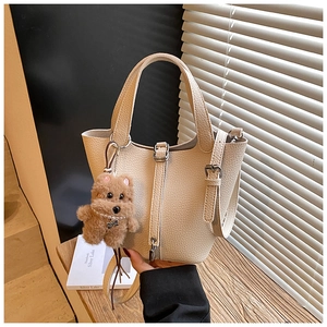 Detalle de bolso cubo beige con textura de grano y un lindo colgante de oso