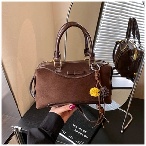 Detail of vintage brown suede Boston bag showing texture and decorative bow charm