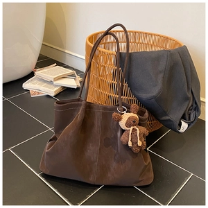 Close-up of vintage brown leather tote bag with a cute knitted bear charm accessory