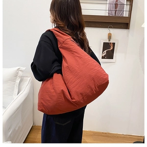 Detail einer großen orangen Canvas-Einkaufstasche mit Reißverschluss an einem Model