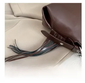 Detail shot of the long dark brown leather tassels and silver metal eyelets on a crossbody bag