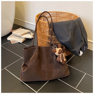 Deep brown tote bag with bear charm and vintage aesthetic on a tiled floor