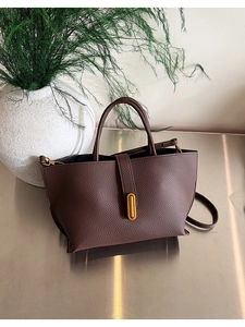 Detail of dark brown lychee leather tote bag with iconic gold metal buckle and hardware