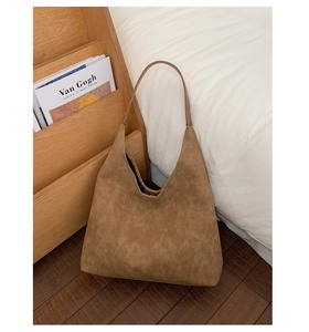 Detailed side view of a large brown suede hobo tote bag in a cozy home setting