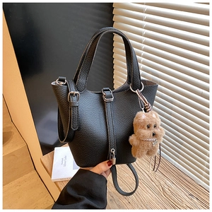 Detalle de bolso cubo en cuero negro con cierre plateado y colgante de oso de peluche